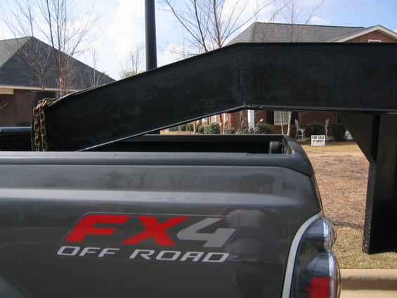 Gray Ford F-250 truck bed with red and silver FX4 Off Road decal, showing a portion of a black trailer hitch and chain