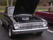 1963 Ford Ranchero - A black 1963 Ford Ranchero is parked next to a red pickup truck, its hood raised to reveal the engine.