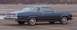 1999 Ford Crown Victoria - A blue coupe with a vinyl roof is parked in an empty lot.