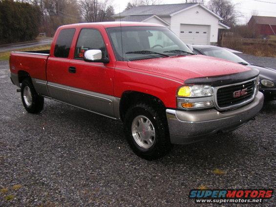 Red GMC Sierra pickup truck, two-tone gray lower body, parked on gravel lot