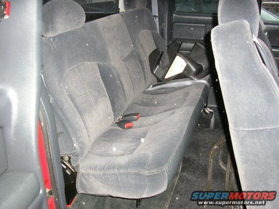 Back seat and floor of a vehicle, with a black plastic item on the seat