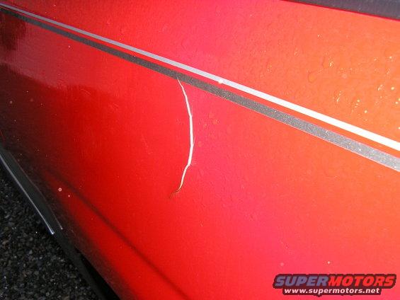 Red 1994 Ford Probe side panel with a paint crack and silver trim