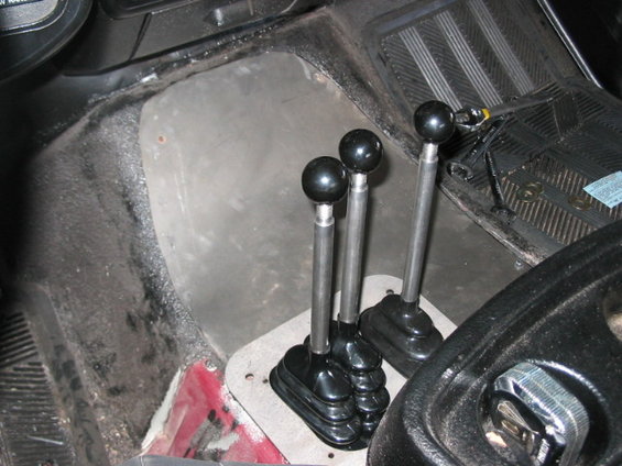 Interior view of three black-knobbed gear shifters in a vehicle