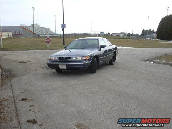 Dark blue 1996 Ford Crown Victoria parked on asphalt, stadium in background