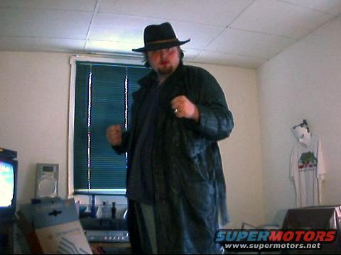Person in a hat and trench coat standing indoors