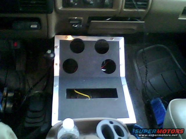 Custom center console with four cup holders and a rectangular cutout, installed in a vehicle interior. Wires are visible in the cutout
