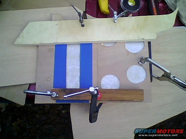 Wooden console part with blue and white stripes, held by clamps