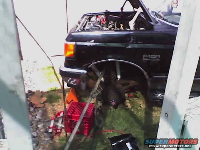 1989 Ford F-150 truck, hood open, front wheel off, being worked on