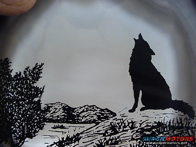 Silhouette of a howling wolf on a rocky hill with mountains and trees, watermarked "SUPERMOTORS.NET"