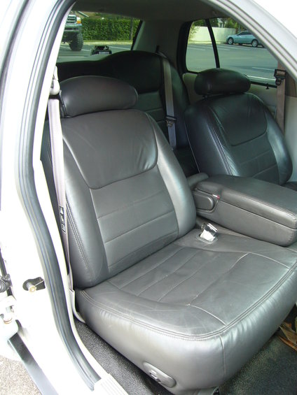 Interior shot of car seats and armrest. Another vehicle is visible through the window