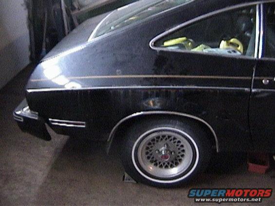 Black 1977 Ford Mustang II hatchback, rear quarter view, showing a gold stripe and wire-spoke wheels