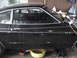 1977 Ford Mustang - Side profile of a black 1977 Ford Mustang coupe, showing its body style and gold trim details.