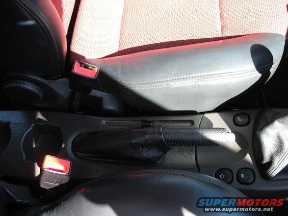Car interior showing seats, seatbelts, and center console with parking brake