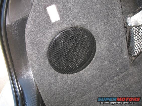 Car interior panel with a round speaker grille and a black mesh cargo net