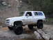 1994 Ford Bronco - This lifted SUV is shown off-roading on a rocky, muddy trail.