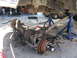 1974 Ford F-100 - The front suspension and axle of a truck are disassembled and supported by jack stands in a workshop.