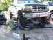 1974 Ford F-100 - A green 1995 Ford F-150 is shown with its front end lifted on jacks, as two individuals work on the suspension.
