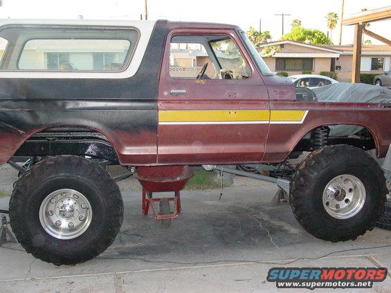 Side view of a lifted Ford Bronco with large off-road tires, undergoing some work
