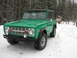 1975 Ford Bronco - A green 1975 Ford Bronco is parked on a snowy path next to a trail marker.