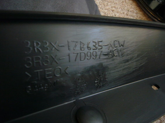 Black plastic automotive part with embossed text 3R3X-17B635-ACW and 3R3X-17D997-ACW