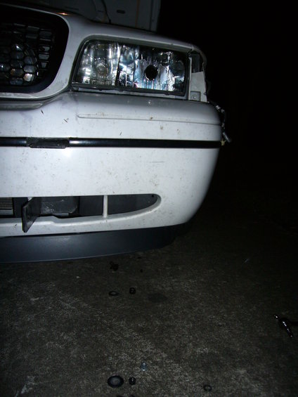 White Ford Crown Victoria front bumper with a damaged headlight and a dark gray lower lip