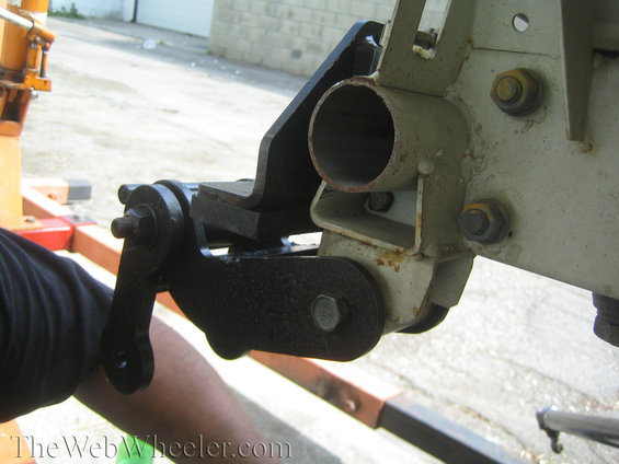 Close-up of a black metal suspension component bolted to a cream-colored frame