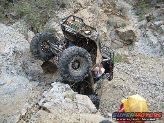 Off-road vehicle on its side in a rocky ravine with a person inside