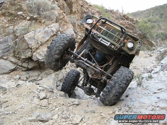 1966 Ford Bronco climbing a steep, rocky hill with one wheel off the ground