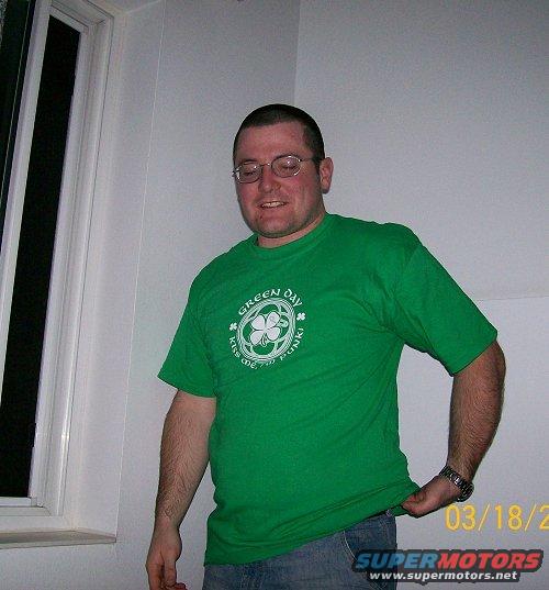Man in green t-shirt with "Green Day" logo, standing indoors