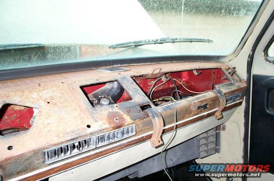 Dashboard of a vehicle with rust and exposed wires. Vents and part of the windshield are visible