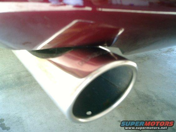 Close-up of a chrome exhaust tip on a dark red car