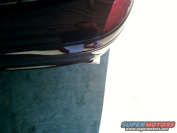 Dark red car bumper with chrome exhaust tip visible