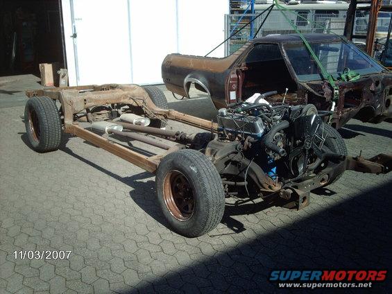Disassembled vehicle chassis with engine and partial body, viewed from the side