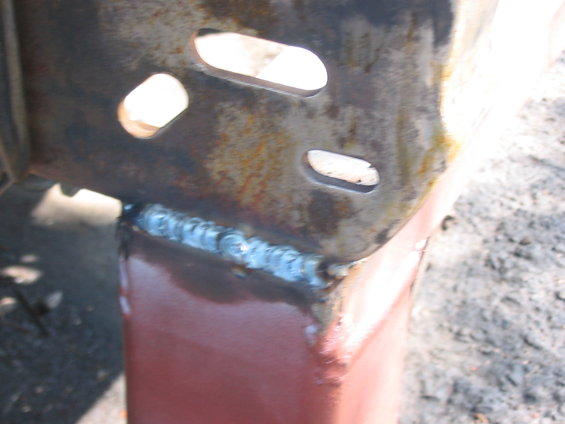 Close-up of a rusty metal bracket with a fresh weld bead