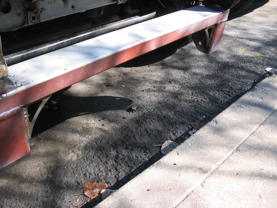 close-up of vehicle frame and red bumper with metal supports underneath