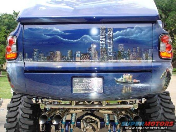 Blue pickup truck rear with airbrushed New York City skyline and twin towers, large tires, and custom exhaust