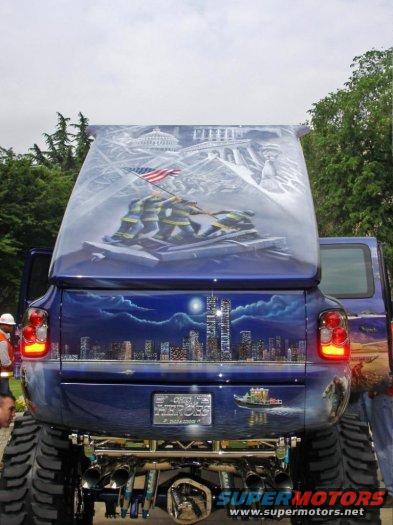 Rear view of a blue truck with a mural of firefighters raising the flag and a city skyline