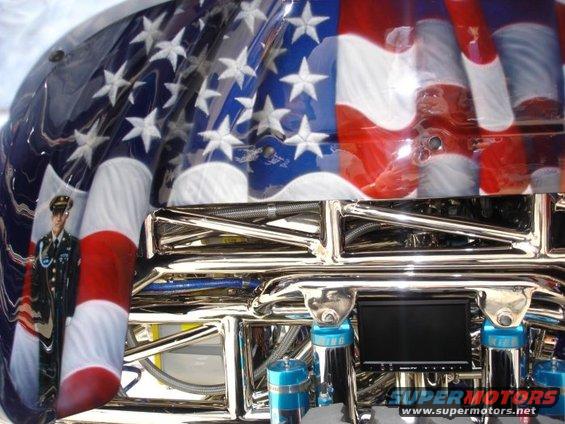 Car interior with American flag paint, a soldier graphic, and shiny chrome parts. Has a small screen and 'SUPERMOTORS' text