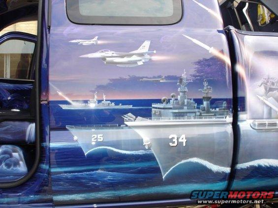 Side view of a truck with a mural of naval ships and fighter jets