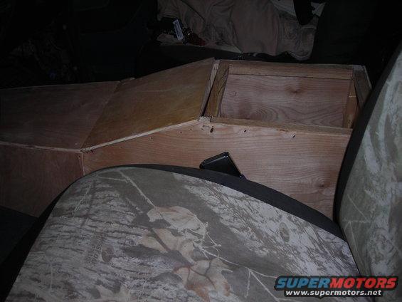 Custom wooden console box in vehicle interior with camouflage seat cover