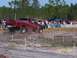 1989 Ford Bronco - A red Nissan pickup truck navigates an off-road course, with spectators watching from the sidelines.