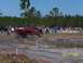 1989 Ford Bronco - Red pickup truck navigates an off-road course with spectators in the background.
