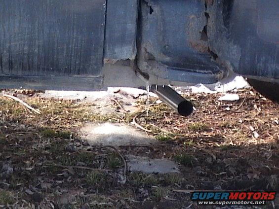 close-up of exhaust pipe and rusted metal on a vehicle's lower body