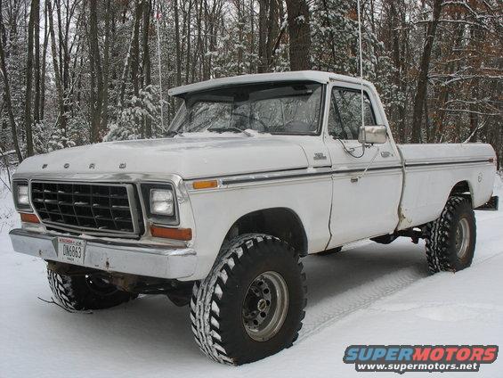White 1979 Ford F-250 pickup truck with large tires in snowy woods