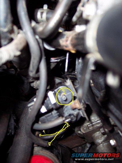 Close-up of engine bay hoses and a sensor with yellow markings
