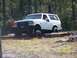 1989 Ford Bronco - White 1989 Ford Bronco navigates an obstacle course with logs and dirt mounds.