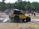 1989 Ford Bronco - A yellow Jeep navigates a challenging obstacle course with spectators observing the event.