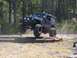 1989 Ford Bronco - A modified Jeep Wrangler jumps over a series of logs during an off-road event.