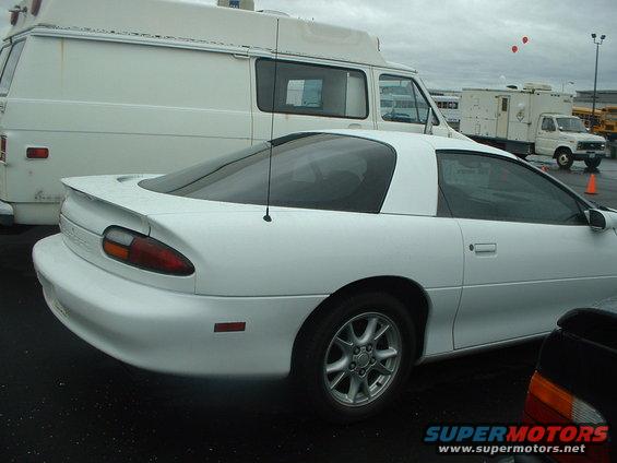White coupe parked next to a white van. The coupe has a spoiler and a black interior