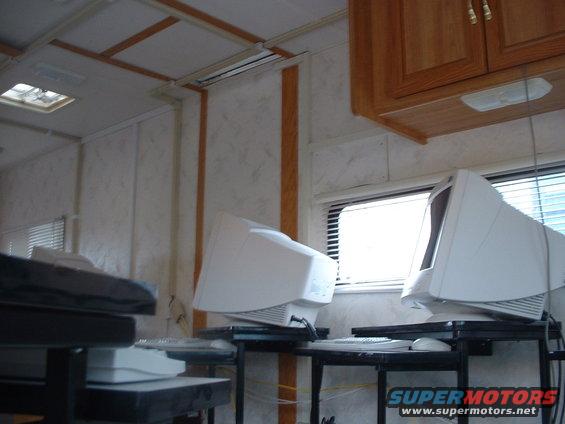 Interior scene with two CRT monitors on desks, blinds on window, and wooden cabinets